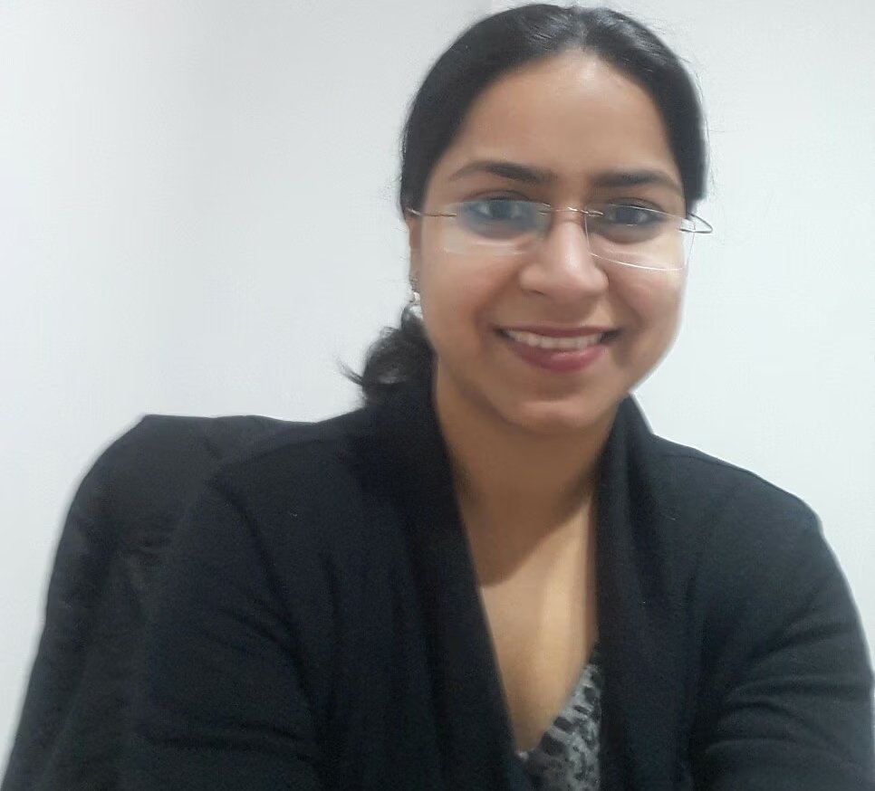 A portrait of Dr Shikha Shivhare, a dermatologist, smiling and wearing glasses.