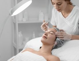 Skin Treatment Injection Procedure A medical professional in gloves injects a substance into a woman's forehead during a skin treatment procedure.